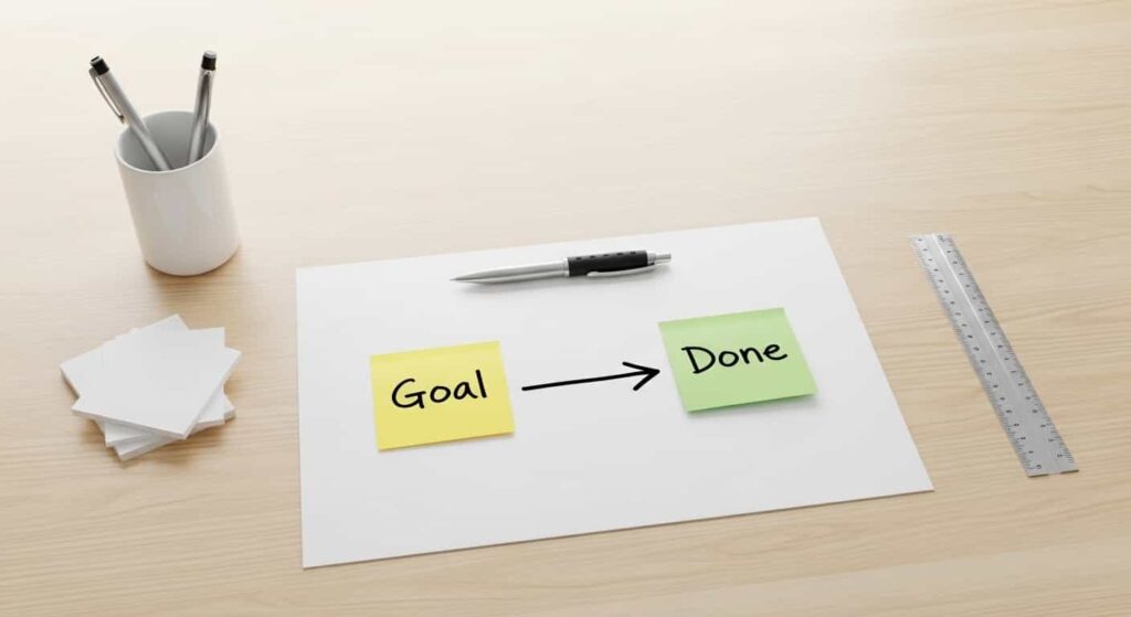 Top-down view of a desk with a paper arrow connecting a goal note to a completed note symbolizing taking action on referrals.